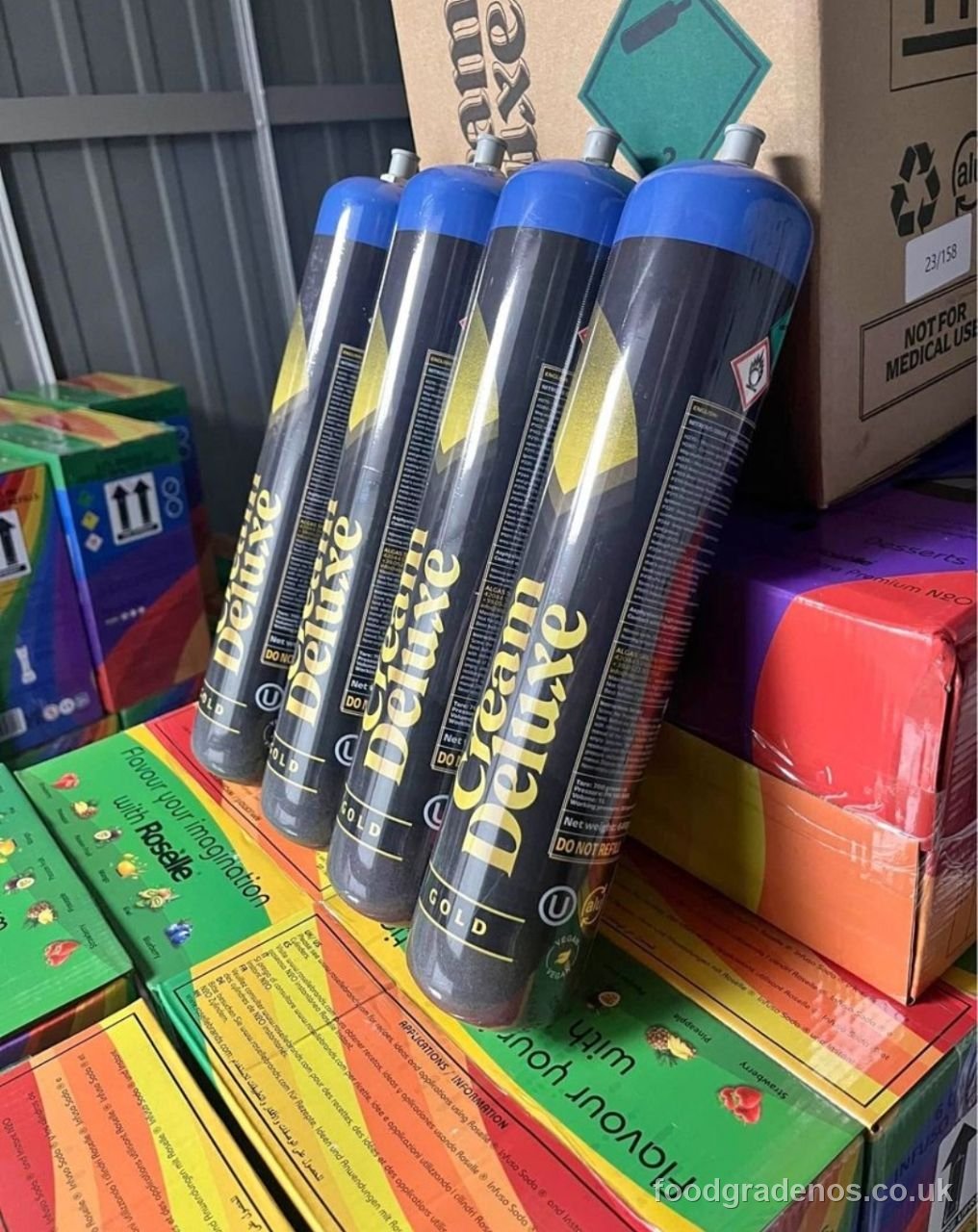 Cases of Cream Deluxe Gold food-grade cylinders stacked for trade orders